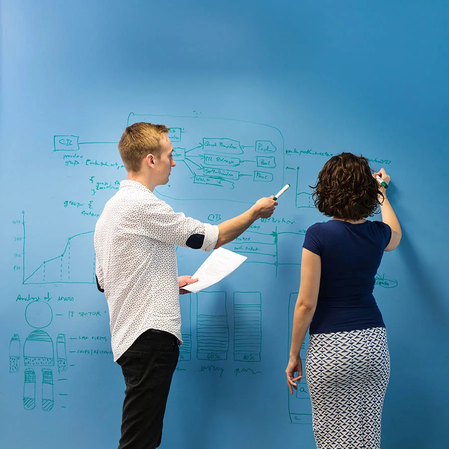 Employees writing on clear whiteboard paint office blue wall