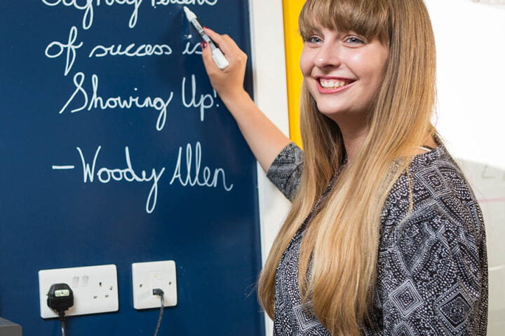 Woman writing on clear dry erase Paint blue office wall