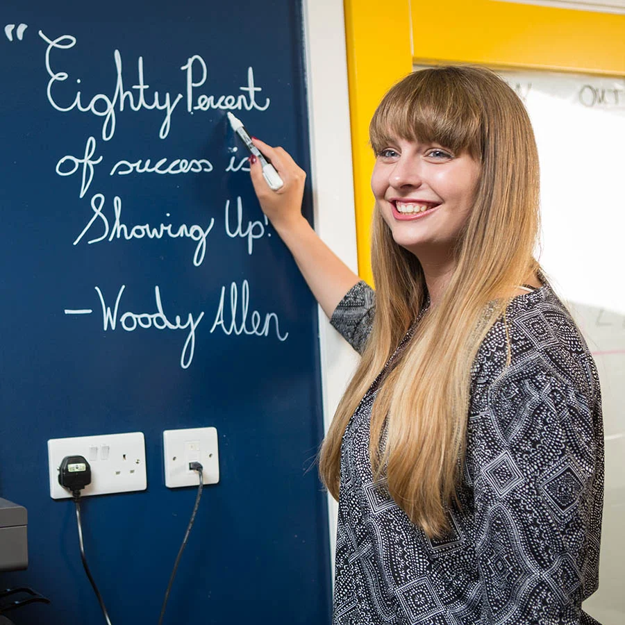 Woman writing on clear dry erase Paint blue office wall