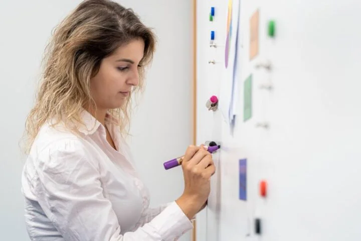 Team member using Magnetic Gray Paint and Whiteboard Paint applied to wall to deliver sales presentation